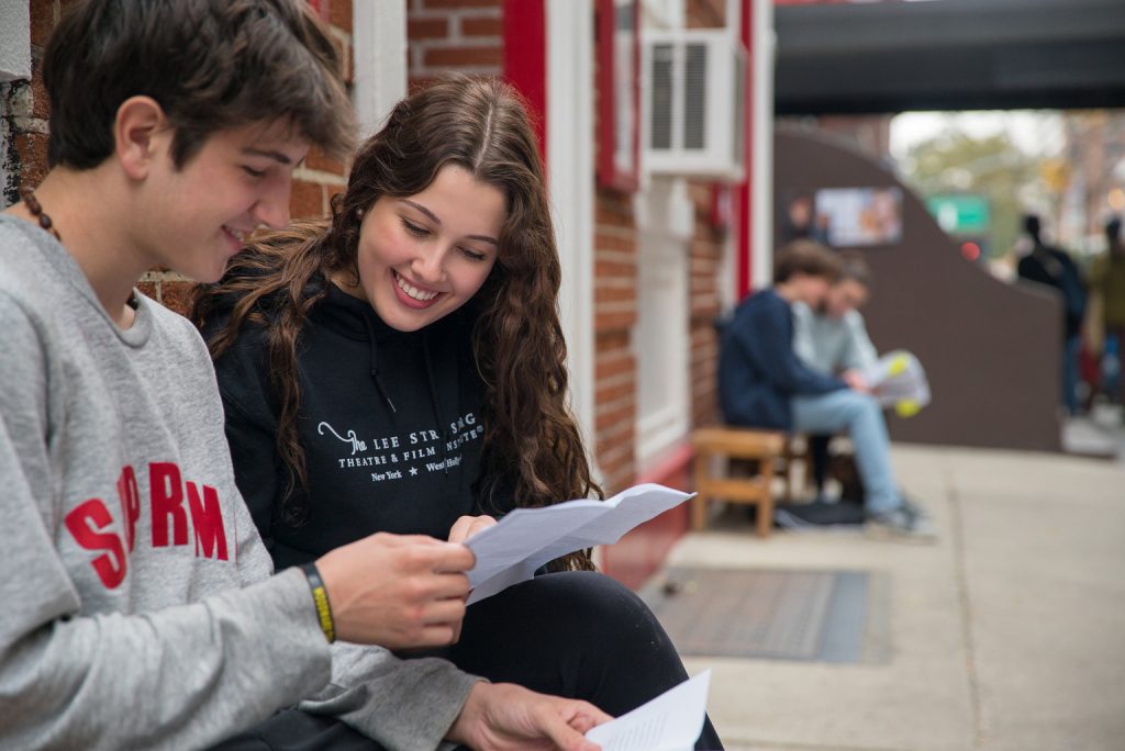 Students on bench reading paper