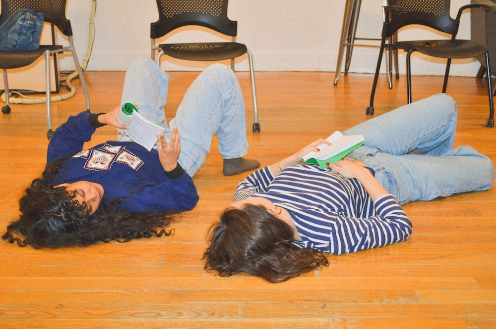 Nuha Jes Izman and Isa Barrett lie on the floor in rehearsal room